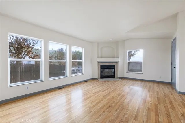 a view of empty room with wooden floor and fireplace