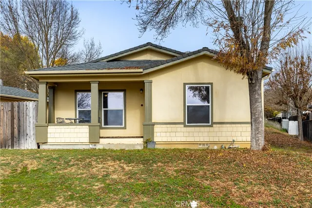 a view of a house with a small yard and large tree