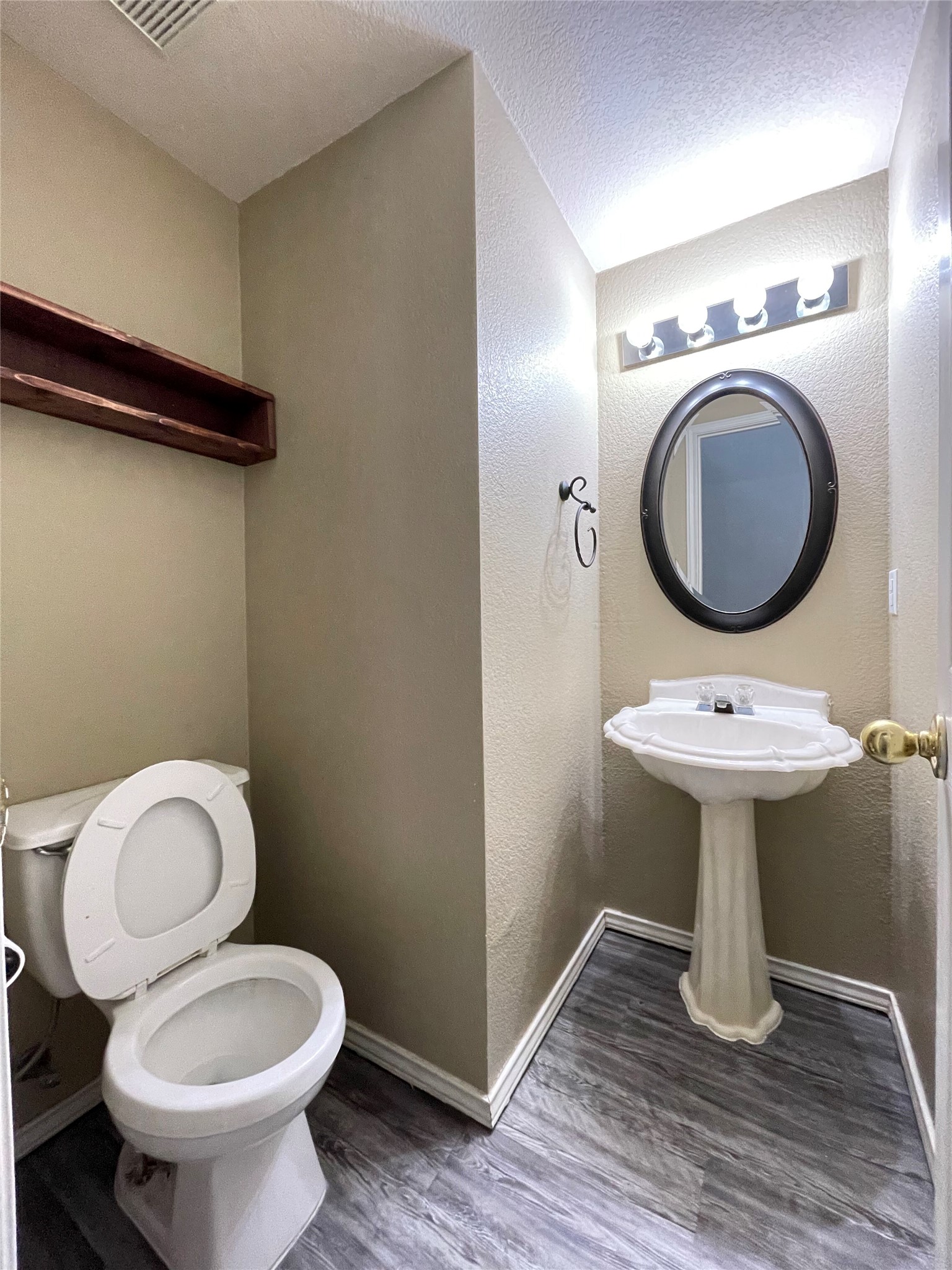 3638 Windhill Loop Round Rock, TX 78681 - Photo 26 of 32 Pedestal sink with an oval mirror and vanity lighting, wood-finish flooring, built-in shelving, and neutral wall tones