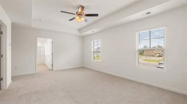 an empty room with windows and ceiling fan
