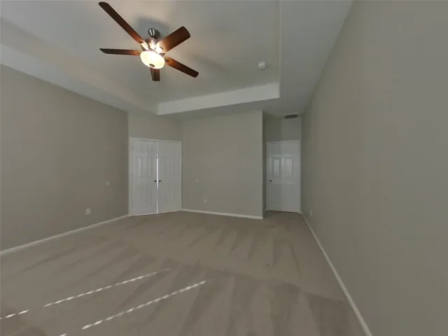 an empty room with ceiling fan and window