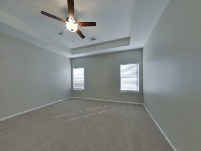 an empty room with a chandelier fan and windows