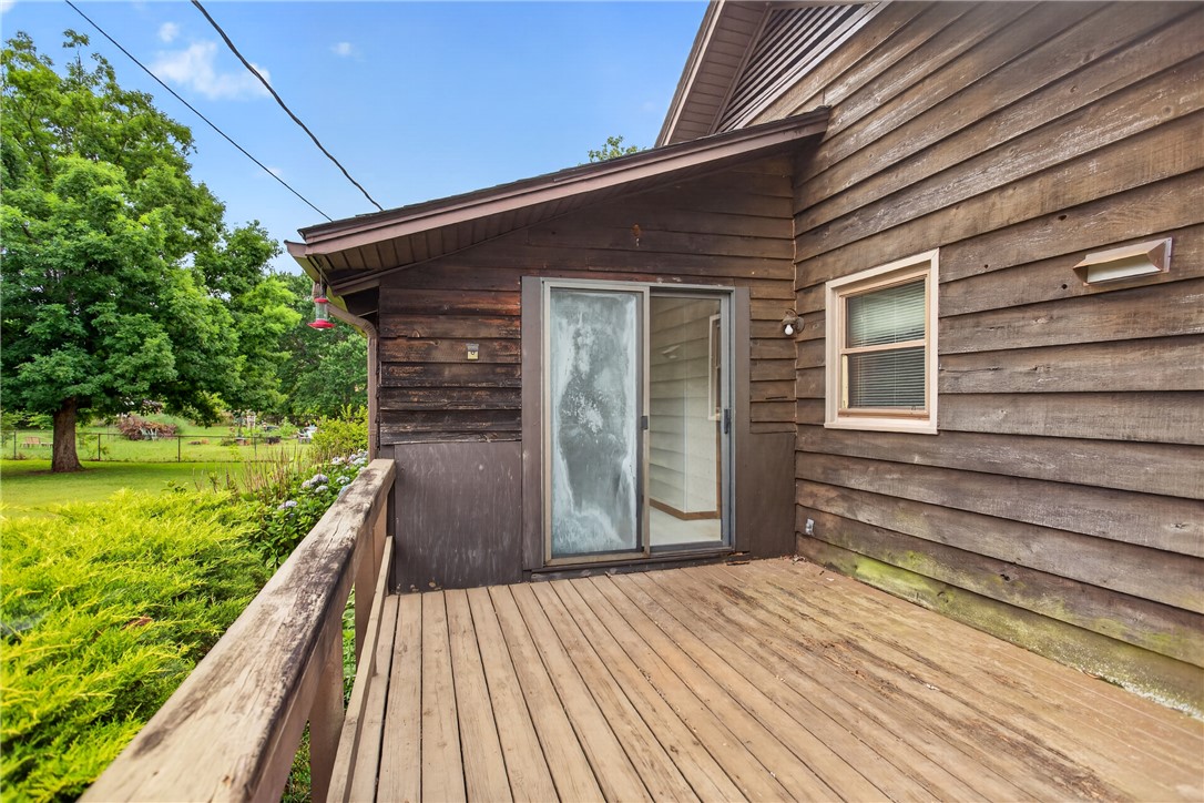 112 Holliday Lane Pendleton, SC 29670 - Photo 33 of 42 A spacious wooden deck extends from a rustic wood-sided home, overlooking a verdant lawn.