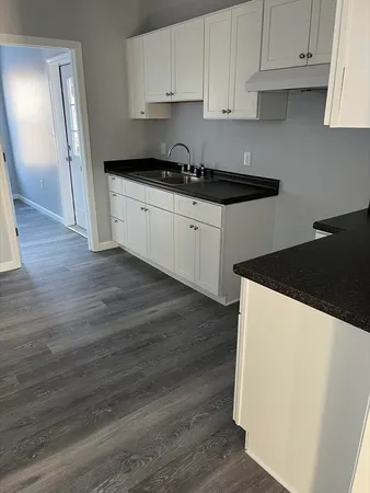 a kitchen with granite countertop a refrigerator sink and cabinets