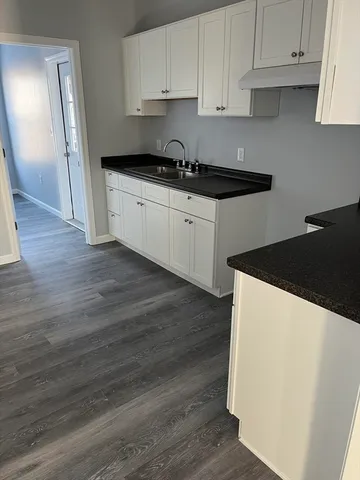 a kitchen with granite countertop a refrigerator sink and cabinets