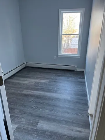 an empty room with wooden floor and window
