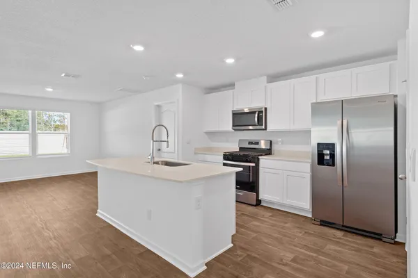 a kitchen with a refrigerator sink and cabinets