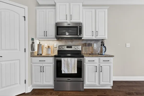 a kitchen with stainless steel appliances granite countertop a stove a microwave and a white cabinets