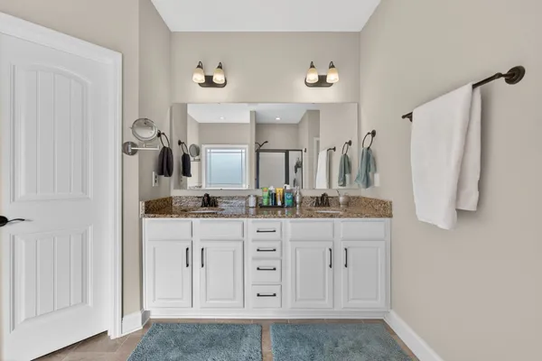 a bathroom with a double vanity sink a mirror a vanity and a shower