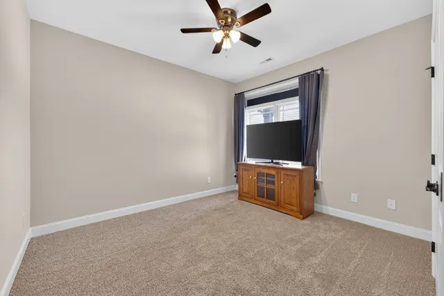 an empty room with windows and ceiling fan