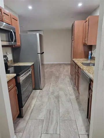 a kitchen with stainless steel appliances granite countertop a refrigerator a stove a microwave a sink and dishwasher