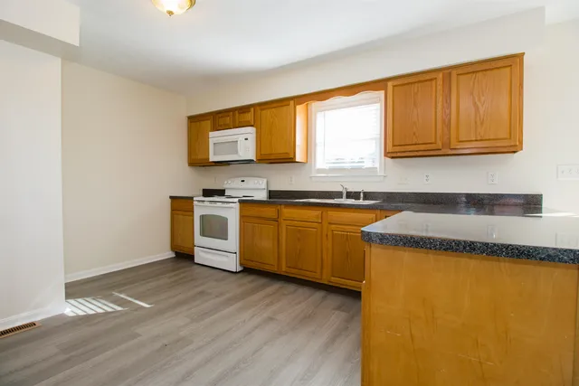 a kitchen with stainless steel appliances granite countertop a sink cabinets and wooden floor