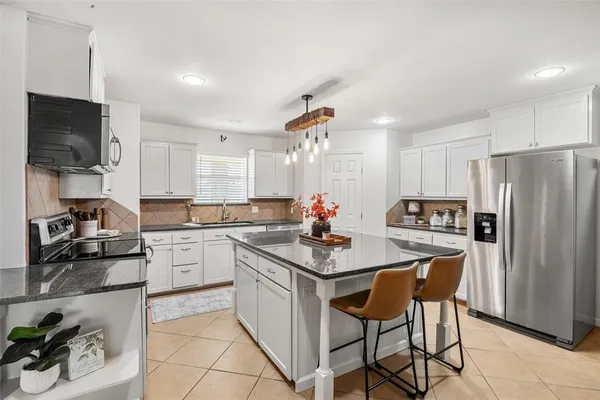a kitchen with refrigerator a sink and chairs