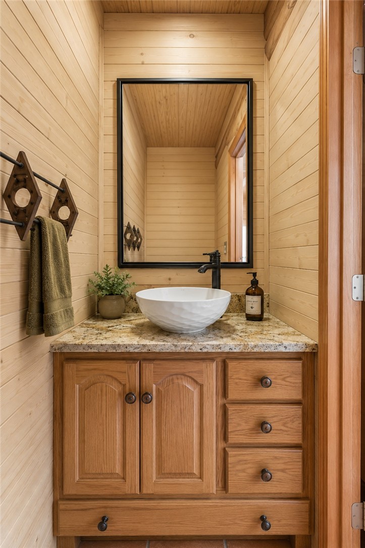 414 Devon Way Anderson, SC 29621 - Photo 13 of 50 A well-lit bathroom showcases a vessel sink on granite counters, complemented by natural wood paneling and cabinetry.