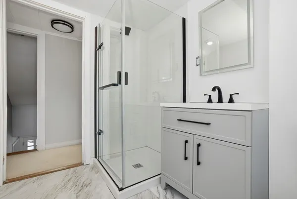 a bathroom with a sink a mirror a vanity and a shower