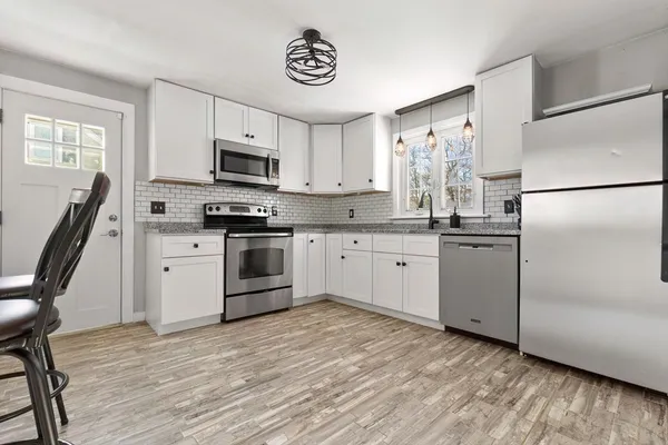 a kitchen with white cabinets stainless steel appliances and a window
