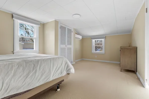 a bed sitting in a spacious bedroom next to a window and a chair