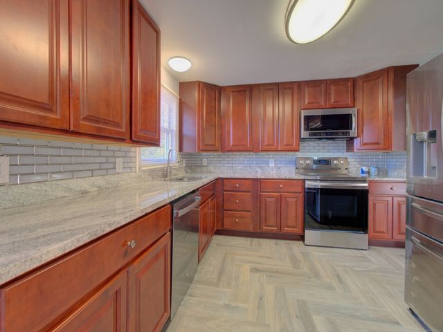 a kitchen with stainless steel appliances granite countertop wooden cabinets a sink and dishwasher with wooden floor