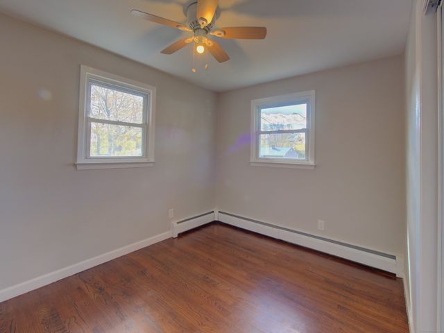 a view of an empty room with window and wooden floor