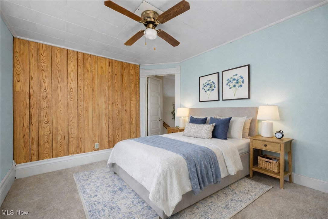 6927 North Wildacre Road Curtice, OH 43412 - Photo 10 of 44 Bedroom featuring wood walls, a ceiling fan, and carpet flooring