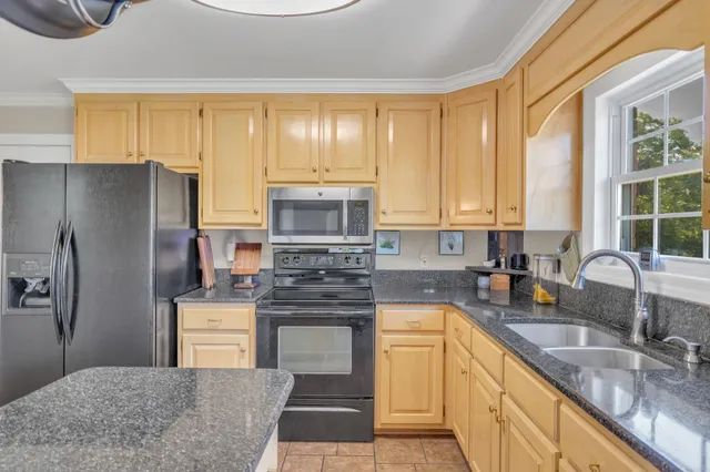 a kitchen with kitchen island granite countertop a sink stove refrigerator and cabinets