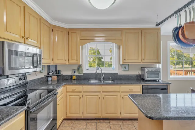 a kitchen with granite countertop a sink a counter top space appliances and cabinets