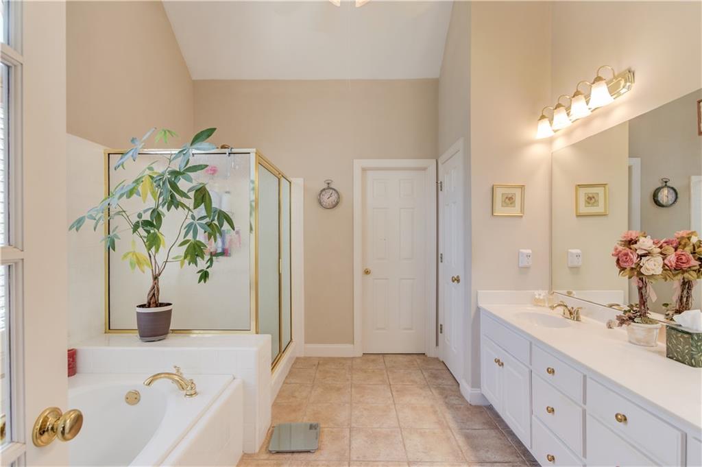 8012 Cypress Point Monroe, GA 30656 - Photo 27 of 67 a spacious en suite bathroom with a granite countertop sink a potted plant and a large mirror