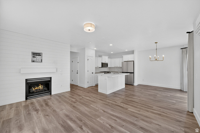 14771 Haddington Road Draper, UT 84020 - Photo 8 of 44 Open-concept living space with wood-finish flooring, a contemporary fireplace with shiplap-style surround, a kitchen island, and stainless steel appliances