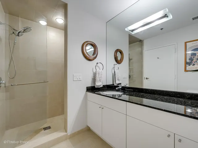 a bathroom with a granite countertop sink a mirror and a shower