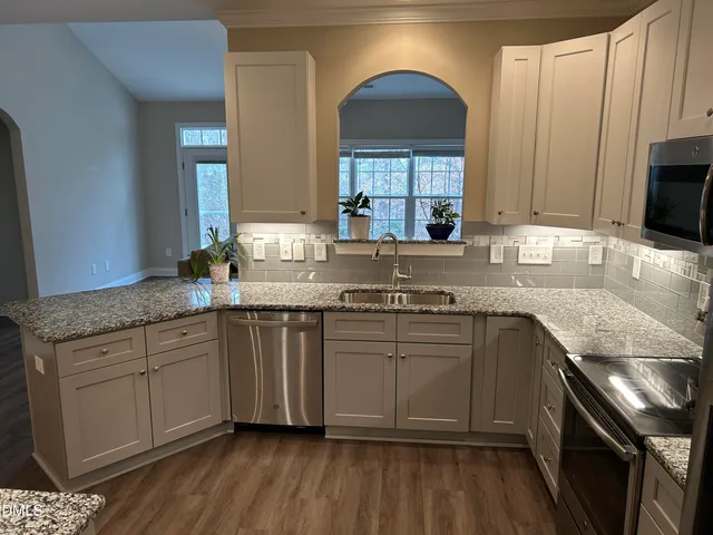 a kitchen with stainless steel appliances granite countertop a stove a sink dishwasher a refrigerator and a oven with wooden floor