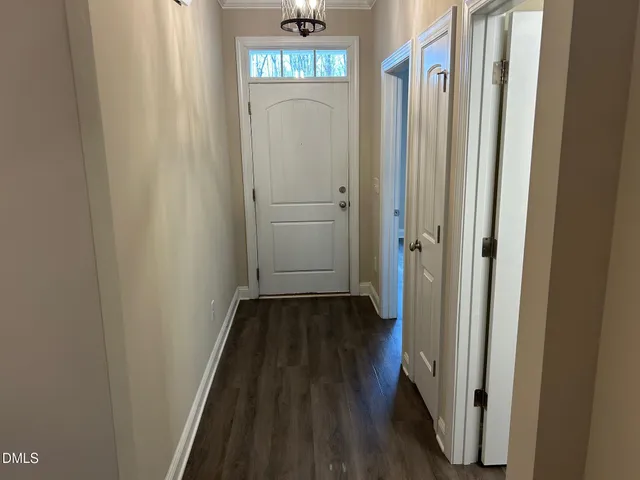 an empty room with wooden floor chandelier and windows