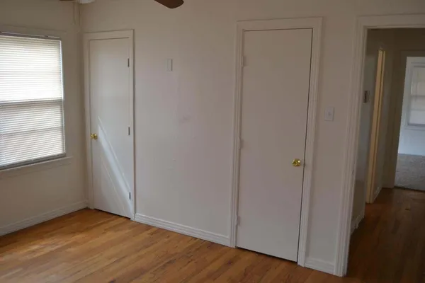 en empty room with wooden floor and fan