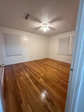 a view of an empty room with window and chandelier fan