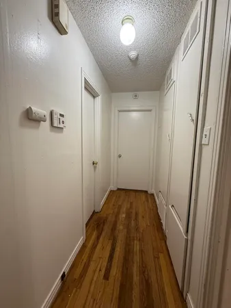 an empty room with wooden floor chandelier fan and windows