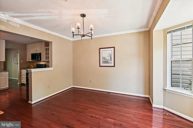 a view of a room with wooden floor chandelier and windows