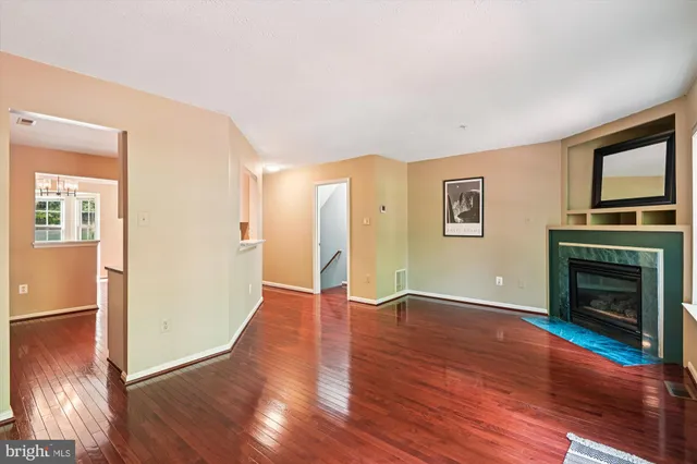 a view of an empty room with wooden floor fireplace and a window