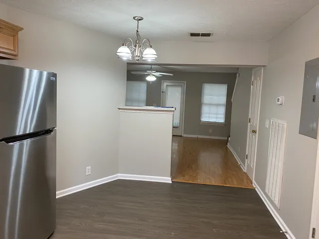 a view of a hallway with wooden floor and chandelier