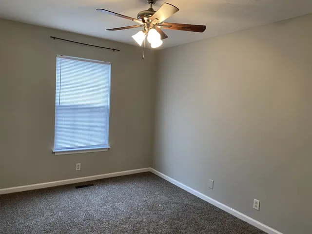 an empty room with a window and a fan