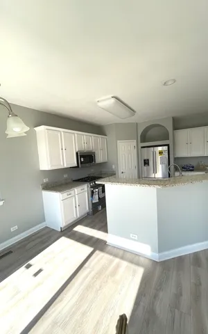 a kitchen with stainless steel appliances kitchen island a large counter top and a wooden floor