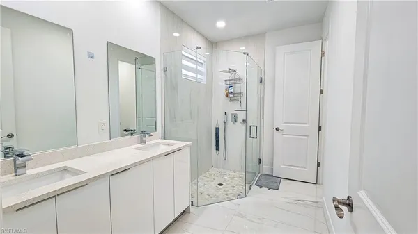 a bathroom with a double vanity sink mirror and shower