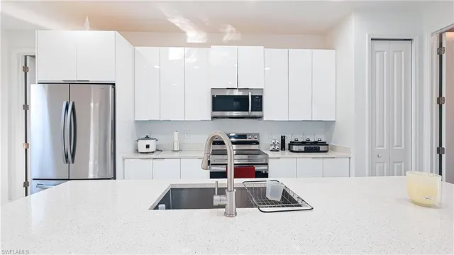 a kitchen with granite countertop a refrigerator stove and white cabinets