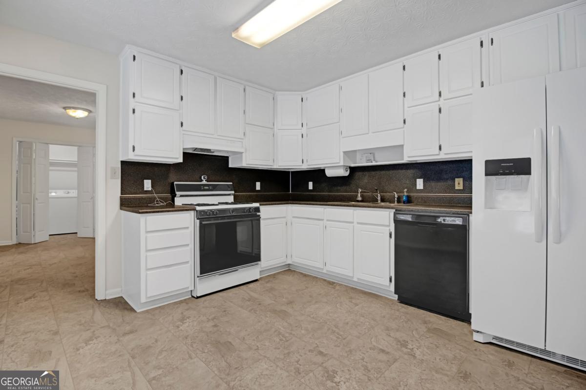145 Deer Ridge Court McDonough, GA 30252 - Photo 13 of 54 a kitchen with white cabinets and white appliances