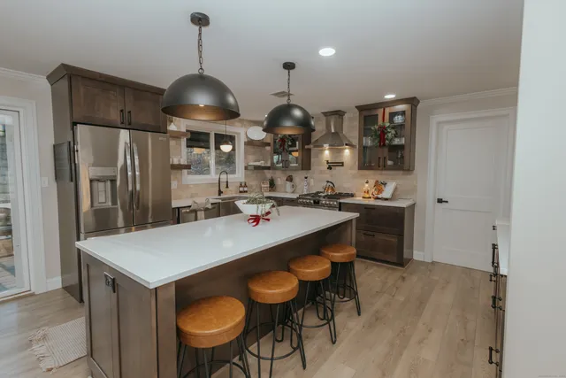 a kitchen with stainless steel appliances granite countertop a stove a refrigerator a sink a dining table and chairs