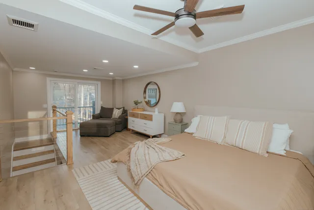 a spacious bedroom with a bed a couch and ceiling fan