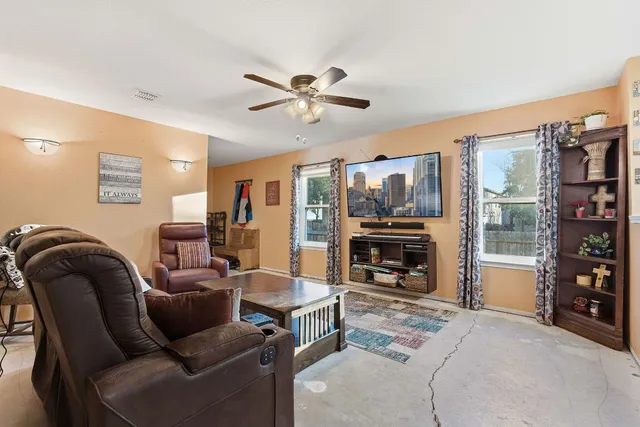 a living room with furniture and a flat screen tv with kitchen view