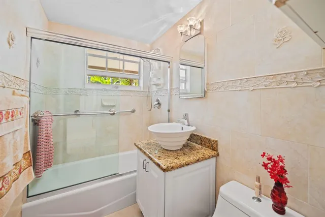 a bathroom with a granite countertop sink and a shower