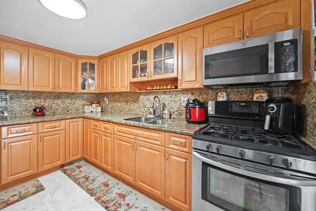 a kitchen with stainless steel appliances granite countertop a stove microwave and sink