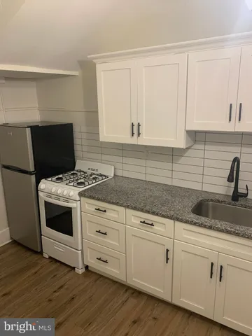 a kitchen with granite countertop white cabinets and white appliances