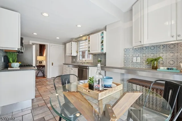 a kitchen with stainless steel appliances kitchen island granite countertop a refrigerator a stove a sink dishwasher and white cabinets with wooden floor