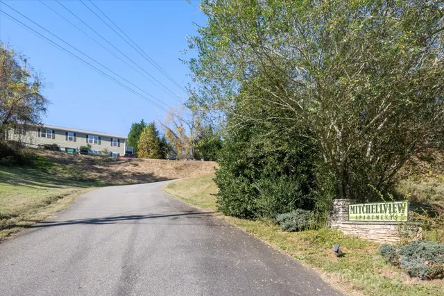 a view of a house with a big yard and large trees